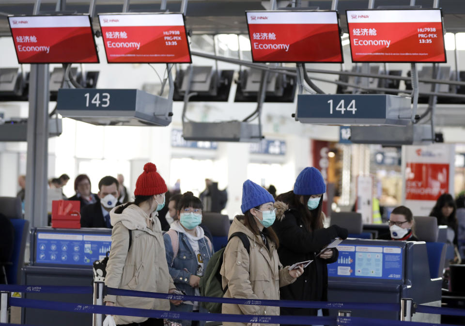 Passengers wearing masks check their boarding passes after checking-in to a flight to Beijing at the Vaclav Havel International Airport in Prague, Czech Republic, Monday, Jan. 27, 2020. Prague's international airport is launching an information campaign for travellers who develop symptoms possibly linked to a new coronavirus illness. (AP Photo/Petr David Josek)