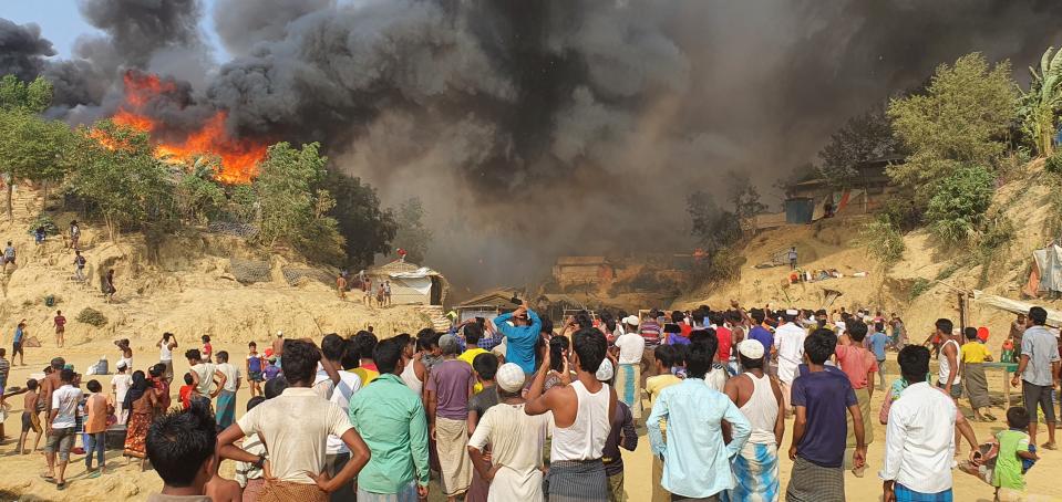 Rohingya refugees watch smoke rising following a fire at the Rohingya refugee camp in Balukhali, southern Bangladesh, Monday, March 22, 2021. The fire destroyed hundreds of shelters and left thousands homeless, officials and witnesses said. (AP Photo/ Shafiqur Rahman)