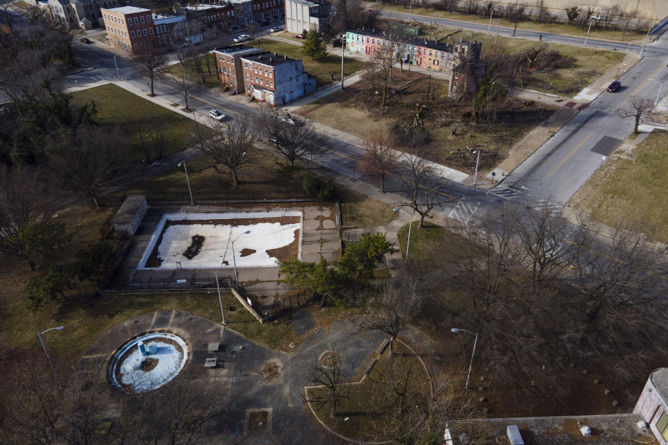 An unkept pool is seen near vacant homes, including one, top left, once rented by Angela Banks, Wednesday, Feb. 15, 2023, in Baltimore. In 2018, Banks was told by her landlord that Baltimore officials were buying her family's home of four decades, planning to demolish the three-story brick rowhouse to make room for an urban renewal project aimed at transforming their historically Black neighborhood. Banks and her children became homeless almost overnight. Banks filed a complaint Monday asking federal officials to investigate whether Baltimore's redevelopment policies are perpetuating racial segregation and violating fair housing laws by disproportionately displacing Black and low-income residents. (AP Photo/Julio Cortez)