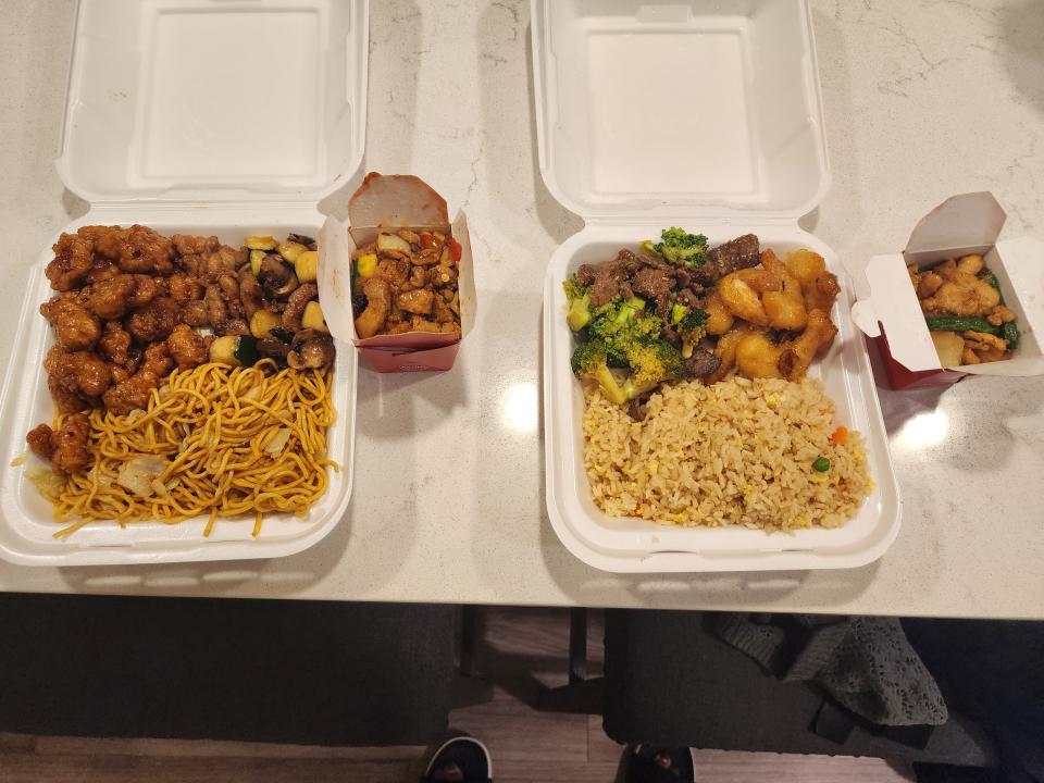 To-go boxes full of chow mein, orange chicken, rice, broccoli beef, and other dishes from Panda Express