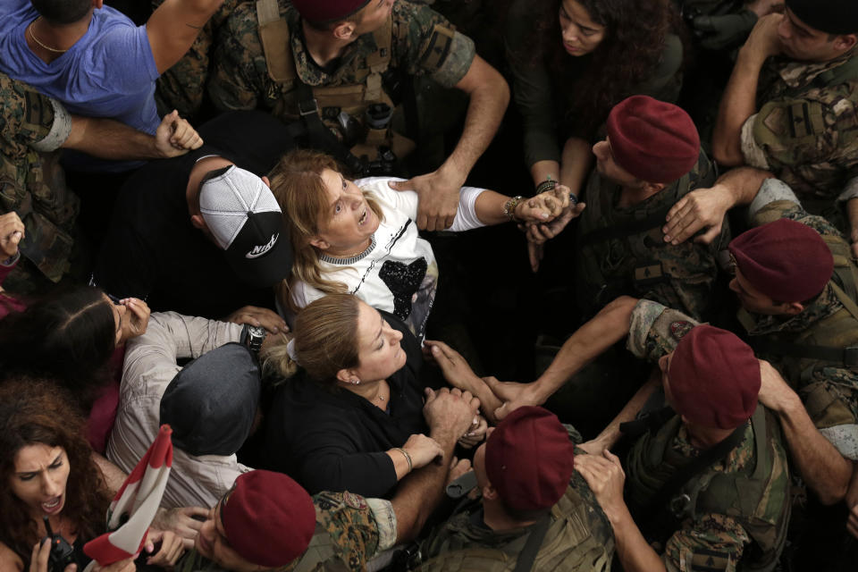 Anti-government protesters scuffle with Lebanese army soldiers during a protest in the town of Jal el-Dib north of Beirut, Lebanon, Wednesday, Oct. 23, 2019. Lebanese troops have moved in to open several major roads in Beirut and other cities, scuffling in some places with anti-government protesters who had blocked the streets for the past week. (AP Photo/Hassan Ammar)