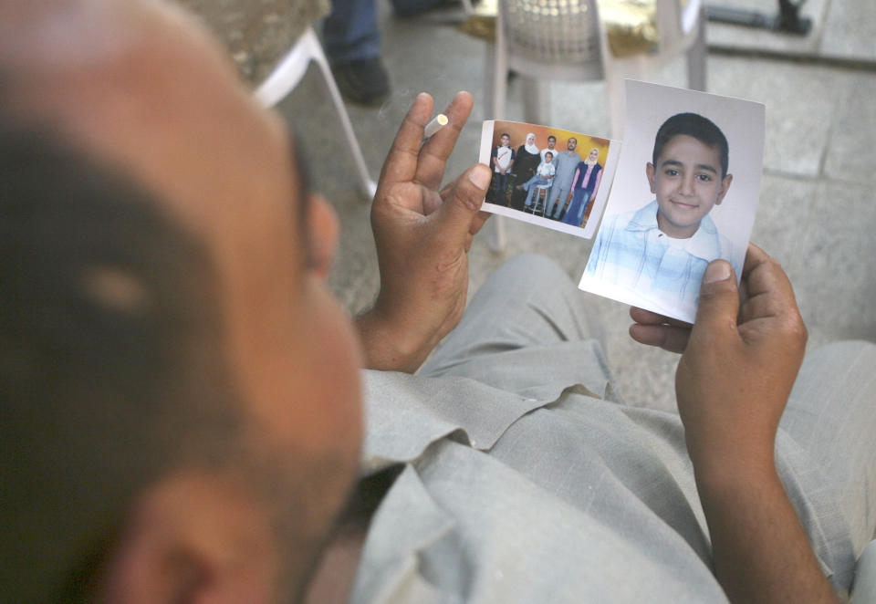 Mohammed Hafiz looks at photos of his 10-year-old son in Baghdad on Oct. 4, 2007. The boy died after the attack on Iraqi civilians by U.S. Blackwater contractors on Sept. 16, 2007. (Photo: AP Photo/Khalid Mohammed)