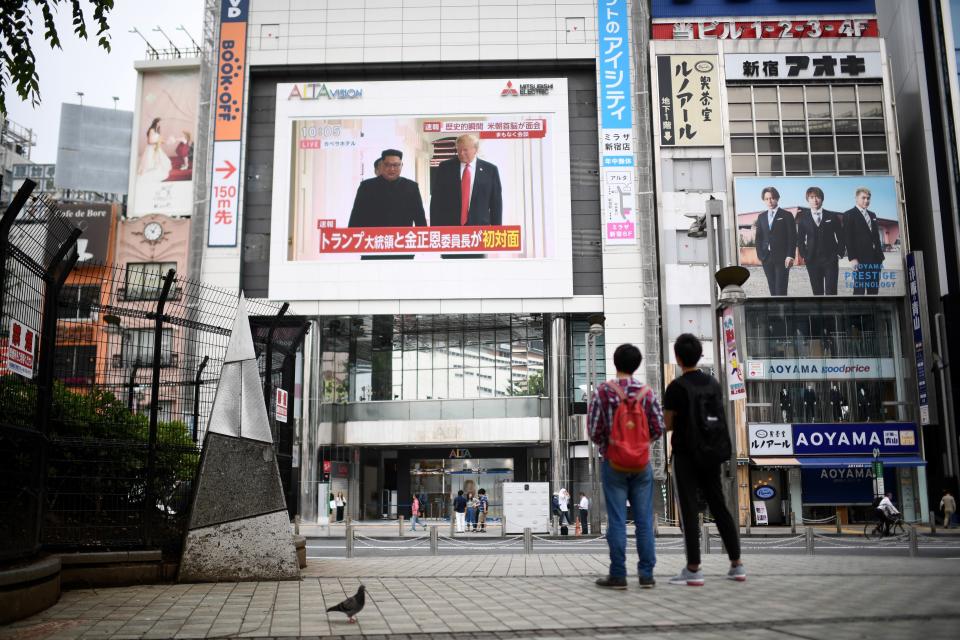 <p>Pedestrians look at a screen displaying live news of meeting between North Korean leader Kim Jong Un and US President Donald Trump, in Tokyo on June 12, 2018. (Photo: Martin Bureau/AFP/Getty Images) </p>