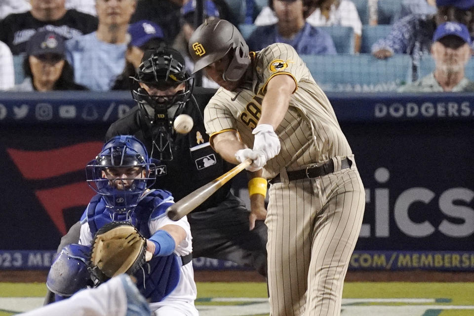 San Diego Padres' Brandon Drury, right, hits a two-run home run as Los Angeles Dodgers catcher Will Smith, left, and home plate umpire Alfonso Marquez watch during the third inning of a baseball game Friday, Sept. 2, 2022, in Los Angeles. (AP Photo/Mark J. Terrill)