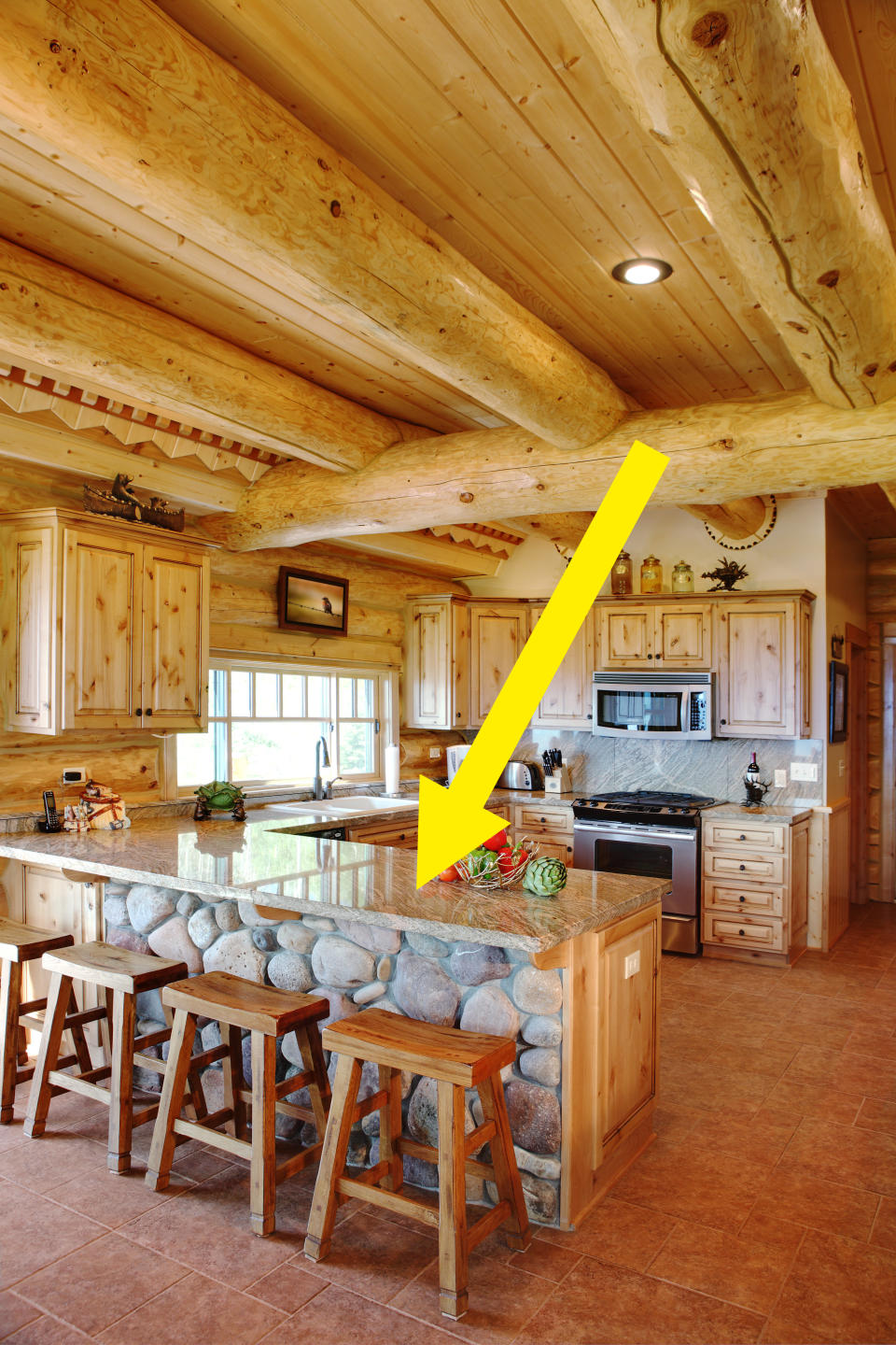 Kitchen and breakfast bar in a large, wood-accented kitchen with light brown granite countertops