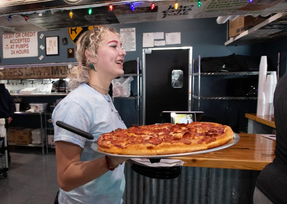 Server Alex Lynn takes a pizza to a table at the newly opened Lost Pizza Co. restaurant on Barrancas Avenue in Pensacola on Wednesday, Dec. 20, 2023.