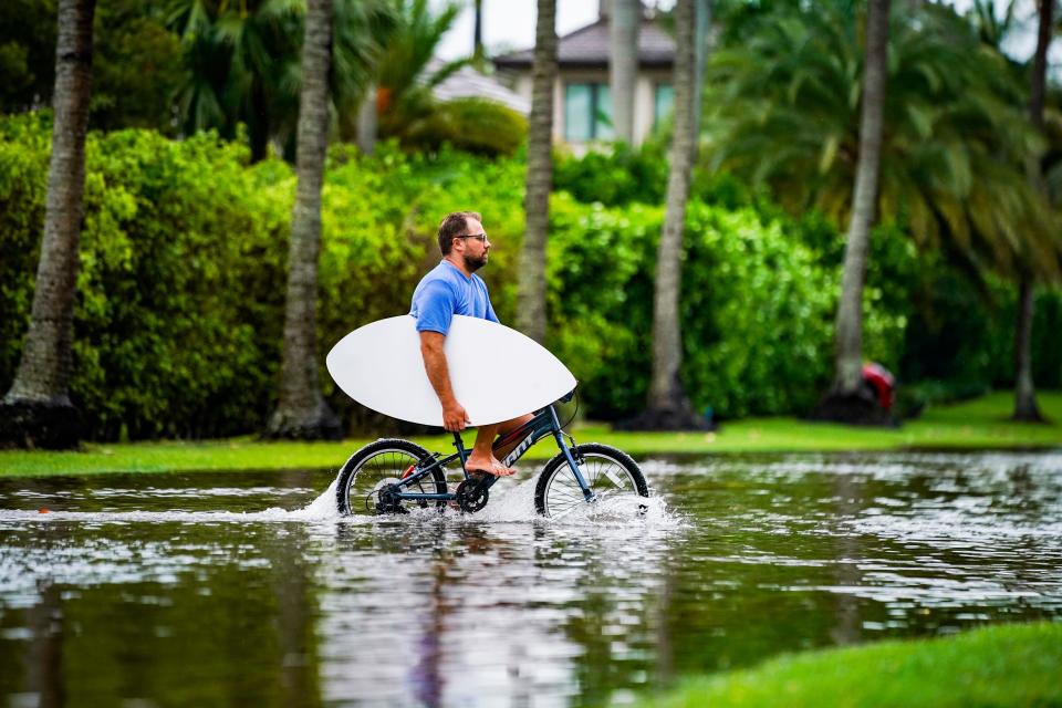 A person rides their bike through a flooded section of Gulf Shore Boulevard South as rain falls in Naples on Tuesday, June 11, 2024.