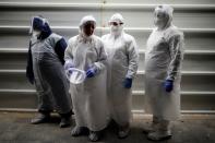 Employees of Chevra Kadisha, the main group that oversees Jewish burials in Israel, stand together as they wear protective gear at a special centre that prepares bodies of Jews who died from the coronavirus disease (COVID-19), at a cemetery in Tel Aviv