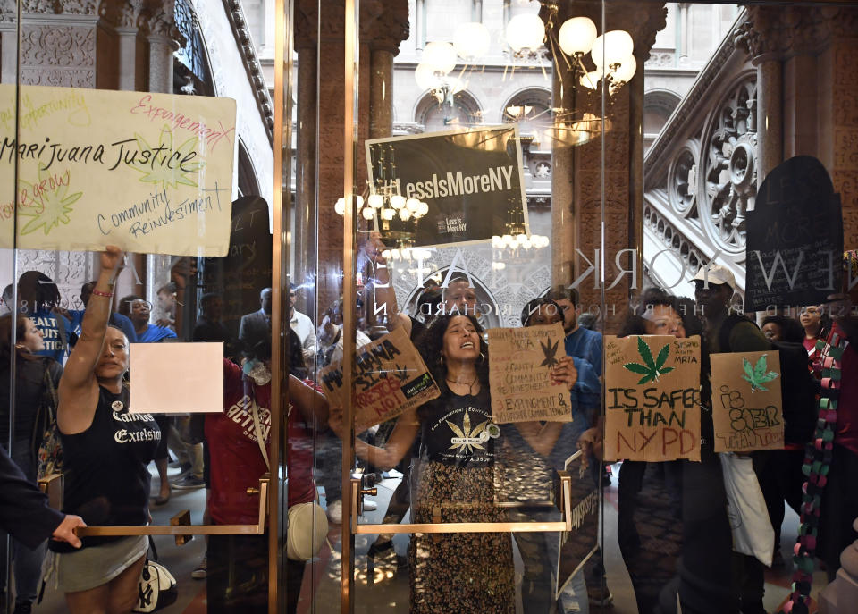 Protesters urging legislators to pass Marijuana legislation holds a signs against the senate lobby doors at the state Capitol Wednesday, June 19, 2019, in Albany, N.Y. (AP Photo/Hans Pennink)