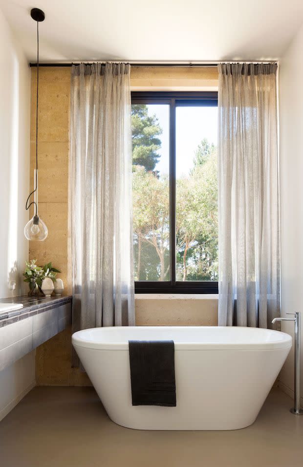 <p>Now this is how you design an approachable yet fancy bathroom. Robson Rak chose the perfect placement for it to be the star: Right beneath the window and flanked by romantic sheers for just a touch of privacy. The low-hanging pendant adds some offbeat charm, too, without stealing the show. </p>