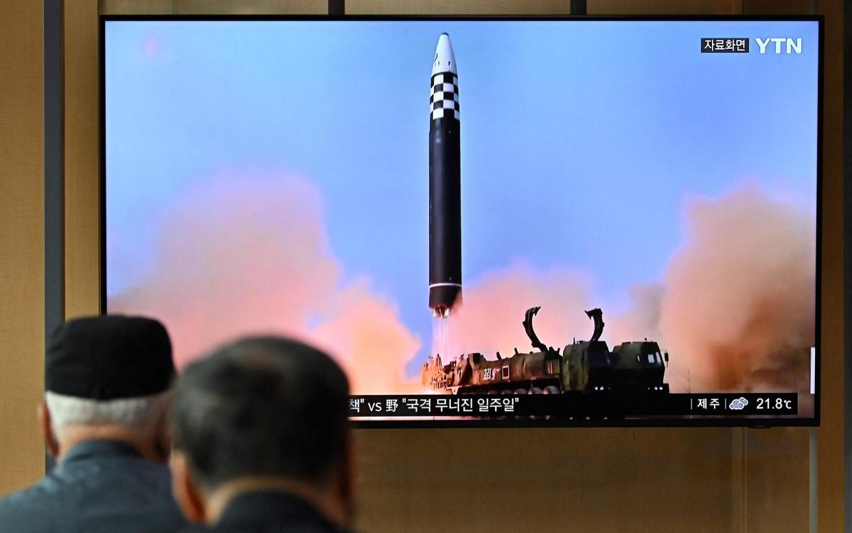 People watch a television screen showing a news broadcast with file footage of a North Korean missile test, following news Pyongyang fired a ballistic missile - AFP