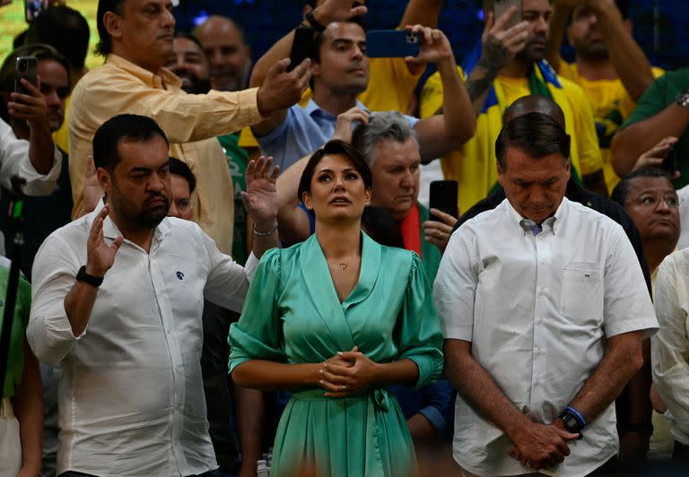 El gobernador de Río de Janeiro, Claudio Castro, la primera dama Michelle Bolsonaro y el presidente Jair Bolsonaro rezan durante la convención del Partido Liberal en julio pasado 