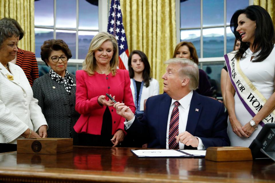President Donald Trump hands a pen to Sen. Marsha Blackburn, R-Tenn., after signing the Women's Suffrage Centennial Commemorative Coin Act during a ceremony in the Oval Office of the White House, Monday, Nov. 25, 2019, in Washington. (AP Photo/Patrick Semansky)