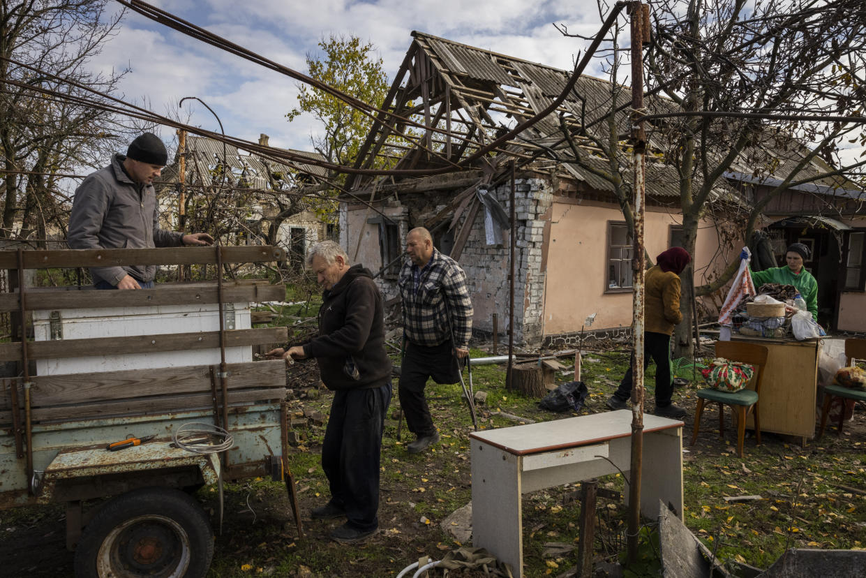 Amigos y familiares ayudan a Anna Moroz, de 80 años, segunda desde la derecha, a rescatar las pertenencias de su casa muy dañada cerca del frente de batalla, en Myroliubivka, en la región de Jersón en Ucrania, el 29 de octubre de 2022. (Ivor Prickett /Los New York Times).