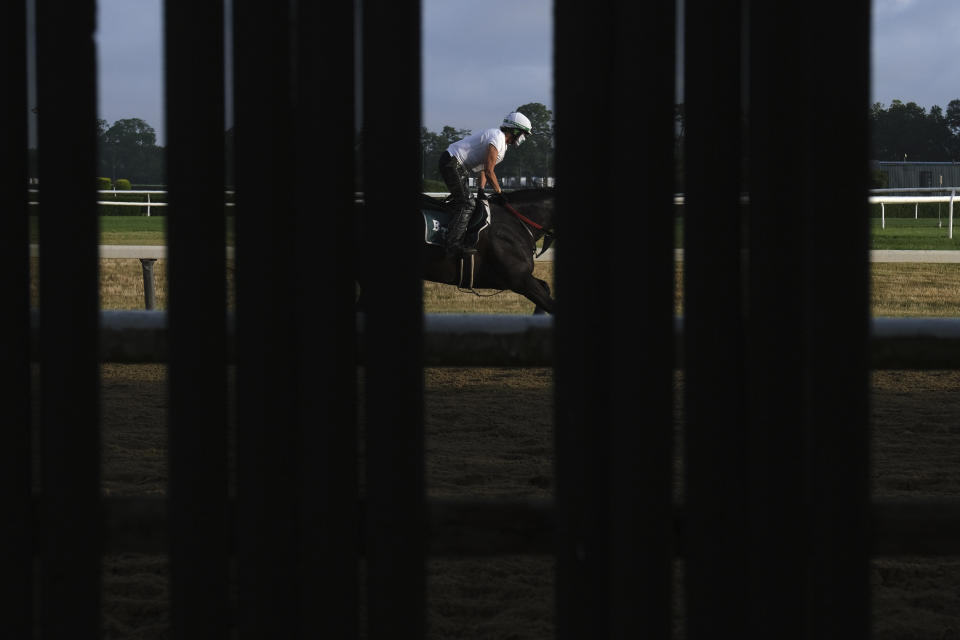 Horses and riders are seen through a fence during workouts at Belmont Park in Elmont, N.Y., Friday, June 19, 2020. The Belmont Stakes is scheduled to run on Saturday. (AP Photo/Seth Wenig)