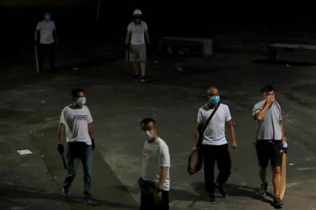 Men in white T-shirts with poles are seen in Yuen Long after attacking anti-extradition bill demonstrators at a train station, in Hong Kong