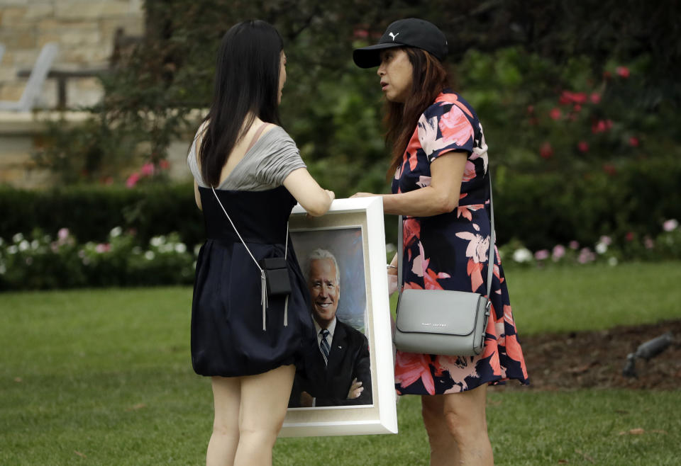 Two women hold a painting of Democratic presidential candidate former Vice President Joe Biden before the start of a fundraiser appearance by Biden Thursday, Sept. 26, 2019, in San Marino, Calif. (AP Photo/Marcio Jose Sanchez)