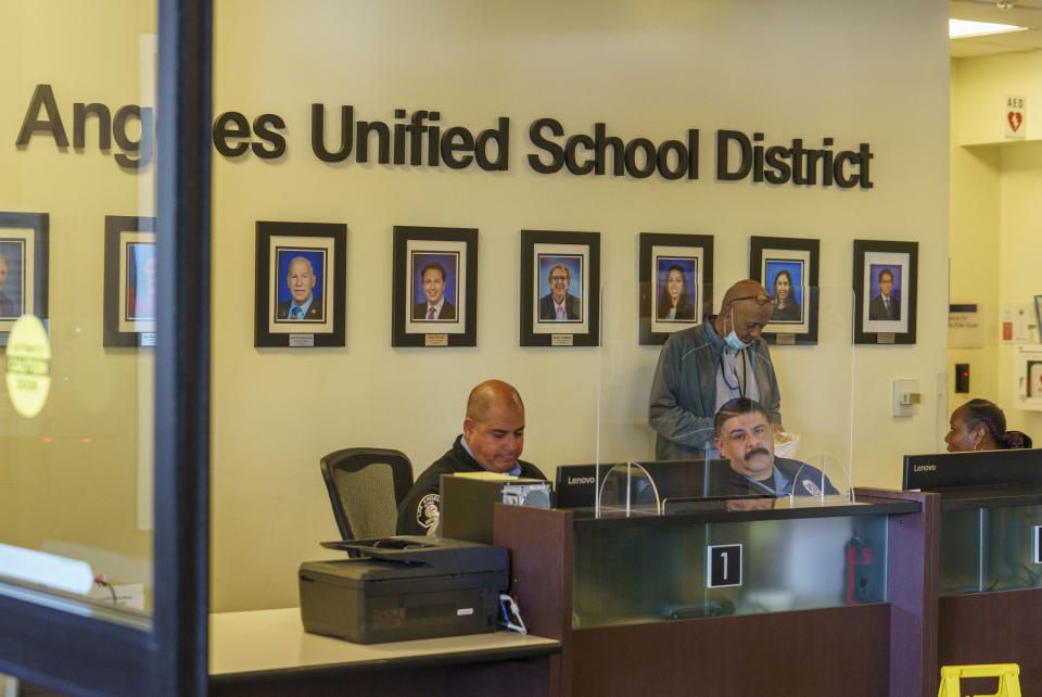 Security officers staff the front desk under portraits of board members of the Los Angeles Unified School District headquarters as thousands of teachers and Service Employees International Union 99 (SEIU) members rally outside the LAUSD headquarters in Los Angeles Tuesday, March 21, 2023. Tens of thousands of workers in the LAUSD walked off the job Tuesday over stalled contract talks, and they were joined by teachers in a three-day strike that shut down the nation's second-largest school system. (AP Photo/Damian Dovarganes)