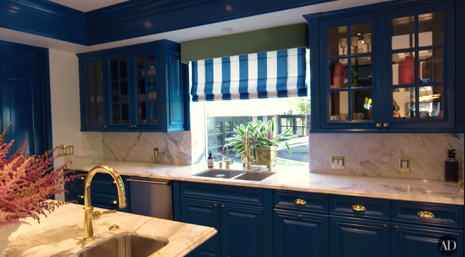 A kitchen with blue cupboards and marble tops