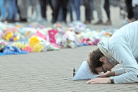 <p>A man prays next to floral tributes at Leicester. Aaron Chown/PA Wire </p>