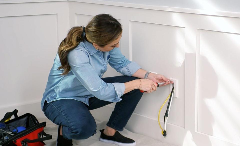 Woman hiding wire behind wall