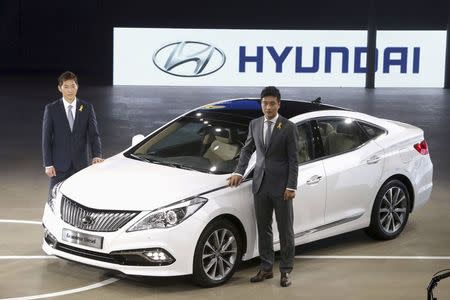 Models pose for photographs with Hyundai Motor Co's diesel version of the Grandeur (Azera) sedan at Busan International Motor Show 2014 in Busan May 29, 2014. REUTERS/Jo Jung-ho/Yonhap