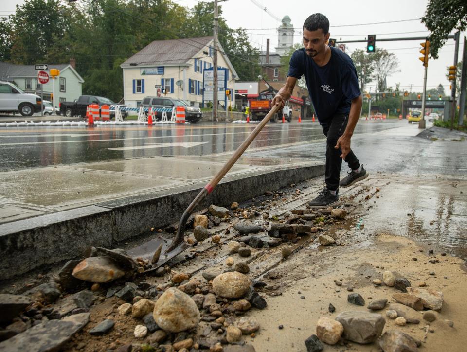 Kidanny Roman shovels mud and gravel from the front of Miles Automotive on Main Street in Leominster after a flash flood Sept. 12, 2023.