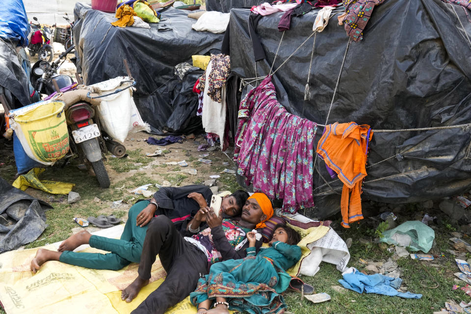 A nomadic family rests in shade outside their tent on a hot summer afternoon in Lalitpur district in northern Uttar Pradesh state, India, Sunday, June 18, 2023. Swaths of two of India's most populous states are under a grip of sever heat leaving dozens of people dead in several days as authorities issue a warning to residents over 60 and others with ailments to stay indoors during the daytime. (AP Photo/Rajesh Kumar Singh)