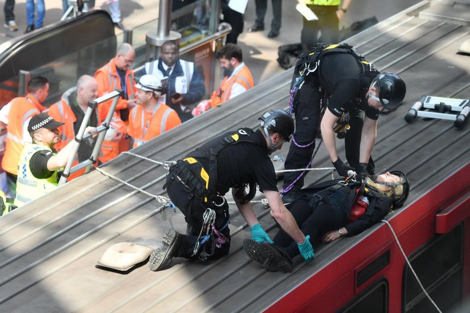 Police remove a woman from the roof of a DLR train at Canary wharf (AFP/Getty Images)