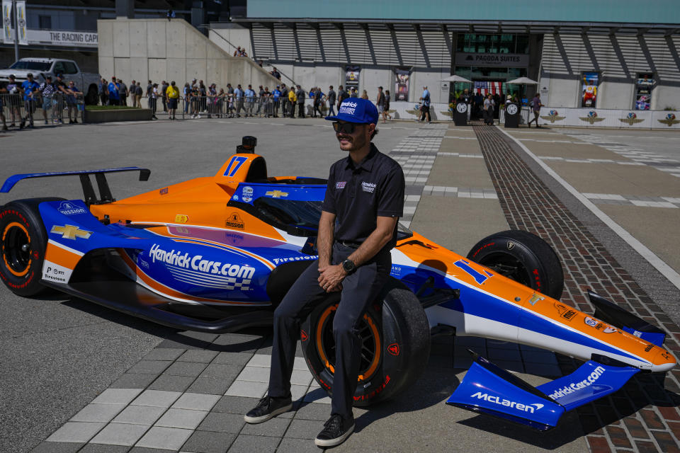 Kyle Larson sits on the car that he will drive in the IndyCar Indianapolis 500 after is was unveiled at Indianapolis Motor Speedway in Indianapolis, Sunday, Aug. 13, 2023. Larson will attempt to drive both the Indianapolis 500 and the Charlotte NASCAR Cup Series auto races on the same day next year. (AP Photo/Michael Conroy)