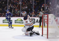 Edmonton Oilers goalie Mikko Koskinen (19), of Finland, allows a goal to Vancouver Canucks' Elias Pettersson, back left, of Sweden, during the second period of an NHL hockey game, Tuesday, Jan. 25, 2022 in Vancouver, British Columbia. (Darryl Dyck/The Canadian Press via AP)