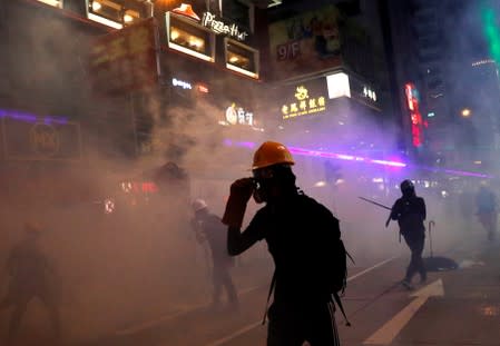 Demonstrators are seen amidst smoke from tear gas during a protest in Hong Kong
