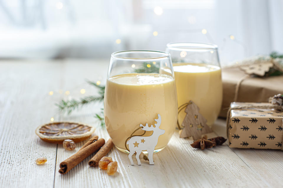 Two glasses of eggnog on a white wooden table by the window. Christmas dessert. Sweet winter cocktail