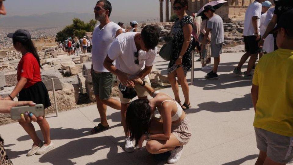 Una mujer en el suelo, afectada visiblemente por el calor. 