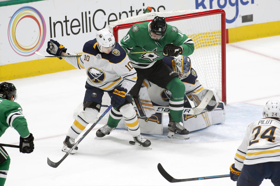 Buffalo Sabres defenseman Henri Jokiharju, left, and Dallas Stars right wing Corey Perry, right, battle for the puck in the crease during the first period of an NHL hockey game in Dallas, Thursday, Jan. 16, 2020. (AP Photo/Ray Carlin)