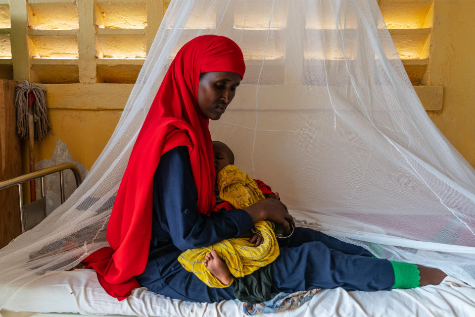 Zaynab sits on a hospital bed in the Doolow Referral Health Center with her 1-year-old, Omar, who is recovering from severe malnutrition. Zaynab, her husband, Hussein, and their four children were recently displaced from the rural area they roamed as nomadic herders in the Gedo region, about 20 miles outside Doolow. (Giles Clarke)