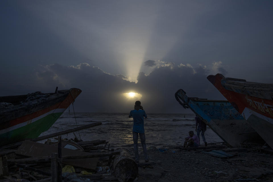 A man takes pictures near a fishing boat as high tide waves hit the Arabian Sea coast at Juhu Koliwada in Mumbai, India, Monday, June 12, 2023. Cyclone Biparjoy, the first severe cyclone in the Arabian Sea this year is set to hit the coastlines of India and Pakistan Thursday. (AP Photo/Rafiq Maqbool)