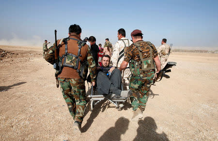 Kurdish Peshmerga fighters carry a wheelchair-bound man, Abbas Ali, 42, after he escaped with his wife and four children from the Islamic State-controlled village of Abu Jarboa, Iraq October 31, 2016. REUTERS/Azad Lashkari