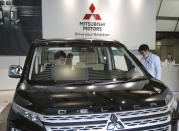 FILE - In this Monday, Nov. 26, 2018, file photo, people look at Mitsubishi car at headquarters of Mitsubishi Motors Corp in Tokyo. German-U.S. automaker Daimler Chrysler bought a 37 percent stake in Tokyo-based Mitsubishi Motors Corp. in 2000, but the alliance felt rocky from the start. Mitsubishi Motors was embroiled in a years-long scandal over its systematic cover-up of auto defects. (AP Photo/Koji Sasahara, File)