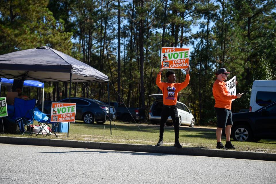 Volunteers with Stand-up and Vote hold signs outside Diamond Lakes on Tuesday, Nov. 8, 2022. 