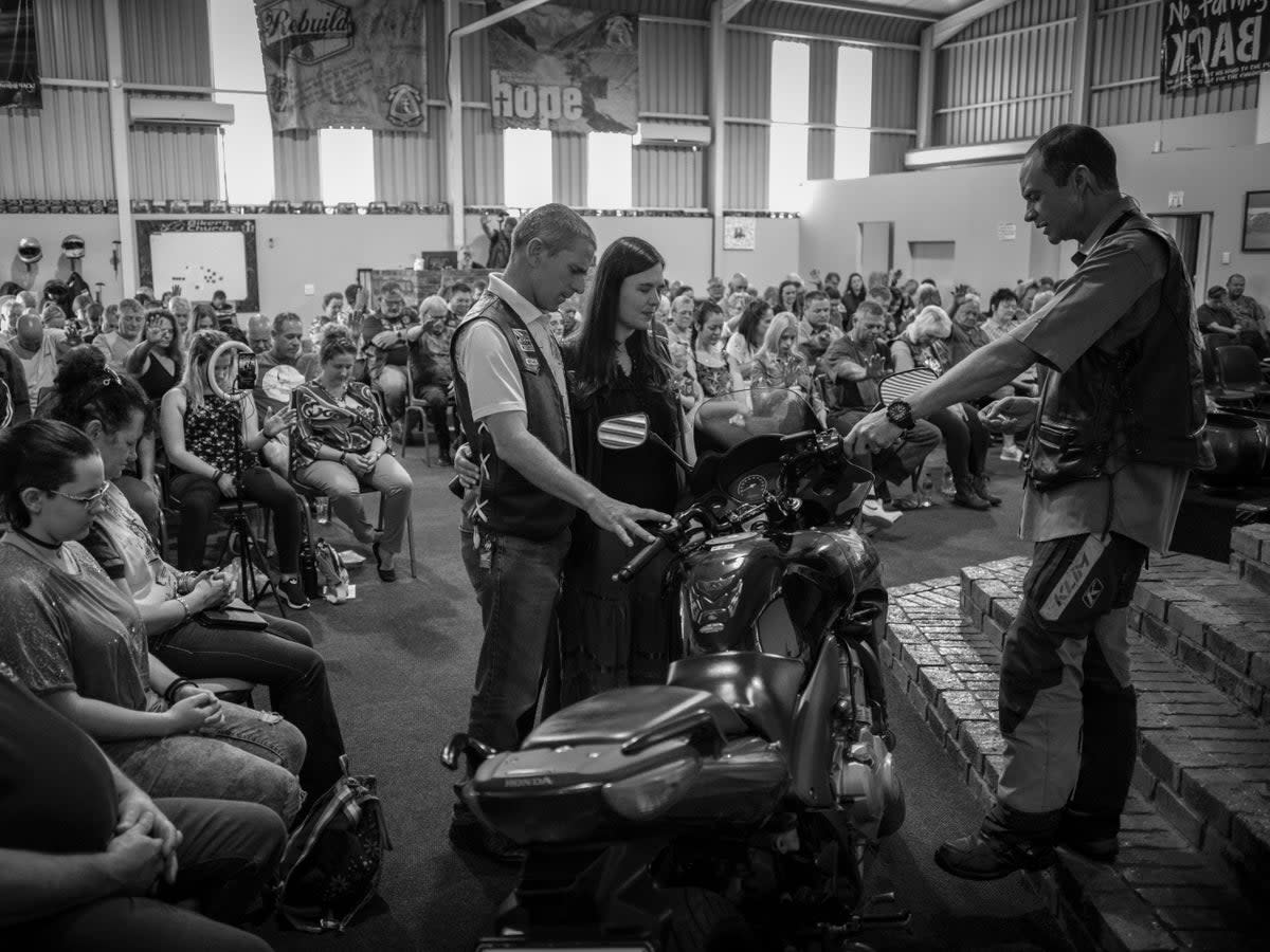 Pastor Mozzy Delpeche (right) leads a prayer for a couple who had recently purchased a new motorcycle at a weekly CMA service in Johannesburg (EPA)