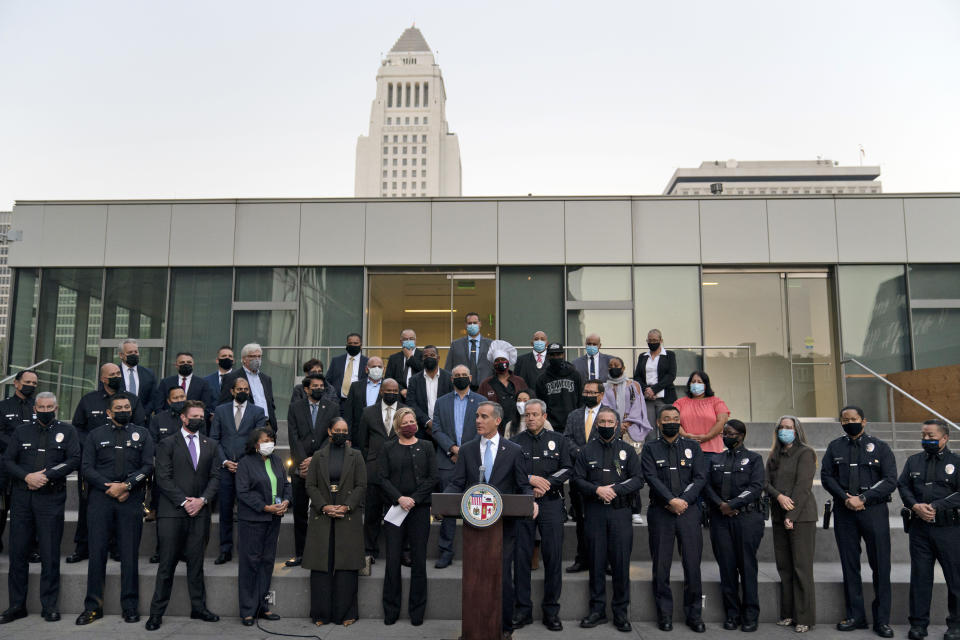 Joined by business owners and community leaders, Los Angeles Mayor Eric Garcetti, center, speaks during a news conference outside the Los Angeles Police Headquarters as City Hall is visible in the background in Los Angeles Thursday, Dec. 2, 2021. Authorities in Los Angeles on Thursday announced arrests in recent smash-and-grab thefts at stores, part of a rash of organized retail crime in California. (AP Photo/Jae C. Hong)