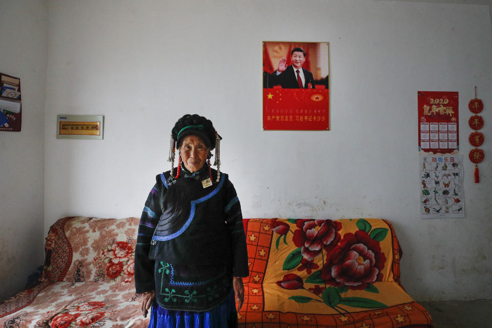 A minority Yi woman stands inside her house displaying a poster of Chinese President Xi Jinping, in Xujiashan village in Ganluo County, southwest China's Sichuan province on Sept. 10, 2020. Communist Party Xi’s smiling visage looks down from the walls of virtually every home inhabited by members of the Yi minority group in a remote corner of China’s Sichuan province. Xi has replaced former leader Mao Zedong for pride of place in new brick and concrete homes built to replace crumbling traditional structures in Sichuan’s Liangshan Yi Autonomous Prefecture, which his home to about 2 million members of the group. (AP Photo/Andy Wong)