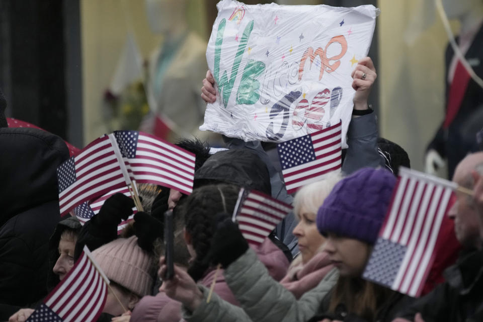 People line the streets with flags and placards in heavy rain as they wait for President Joe Biden to arrive for events in Dundalk, Ireland, Wednesday, April 12, 2023. President Biden is three day visit to Ireland. (AP Photo/Christophe Ena)