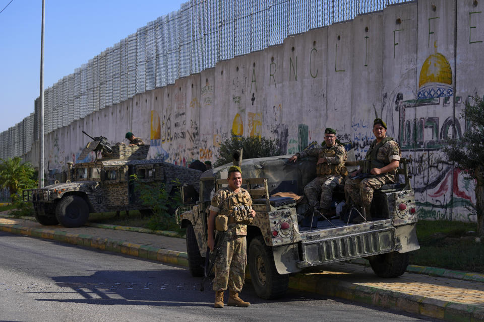 Lebanese army soldiers sit on their armored vehicles next to the wall that separates Lebanon from Israel in the southeastern Lebanese village of Kfar Kila, Lebanon, Friday, Oct. 13, 2023. Sporadic acts of violence have been reported over the past days along the tense Lebanon-Israel border. (AP Photo/Bilal Hussein)
