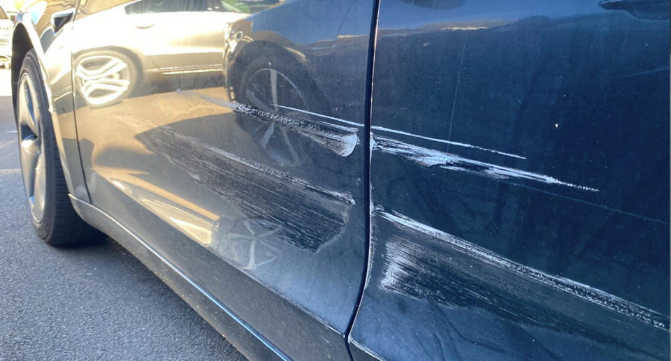 The black Tesla can be seen with scratches along its side. 