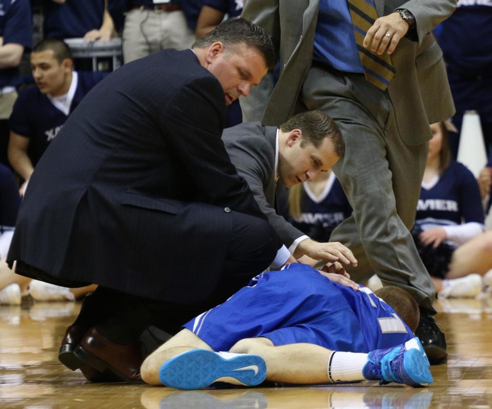 Creighton coach Greg McDermott, left, checks on Isaiah Zierden during the first half of an NCAA college basketball game against Xavier in Cincinnati on Saturday March 1, 2014. (AP Photo/Tom Uhlman)