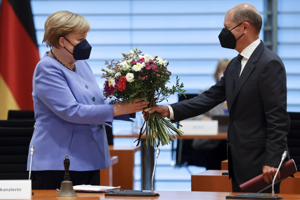 German Finance Minister Olaf Scholz hands a bouquet of flowers to German Chancellor Angela Merkel on occasion of her birthday on July 17, as they arrive for the weekly German cabinet meeting at the Chancellery in Berlin, Germany, Wednesday, July 21, 2021. (Axel Schmidt/Pool Photo via AP)