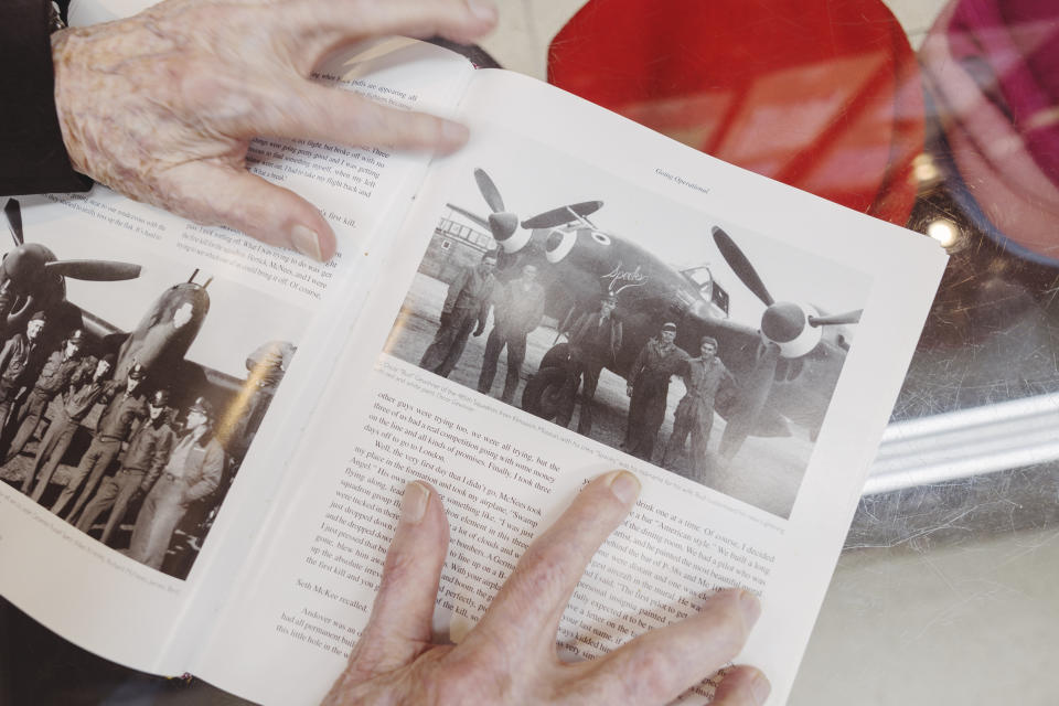 Sam Meyer of Meyer the Hatter looks at a World War II history book on the 370th Fighter Group, a group that he was part of, on Friday, Feb. 23, 2024 in New Orleans. He is in this photograph, second from the right, in front of a P-38 Lightning twin-engine fighter aircraft. (Chris Granger/The Times-Picayune/The New Orleans Advocate via AP)