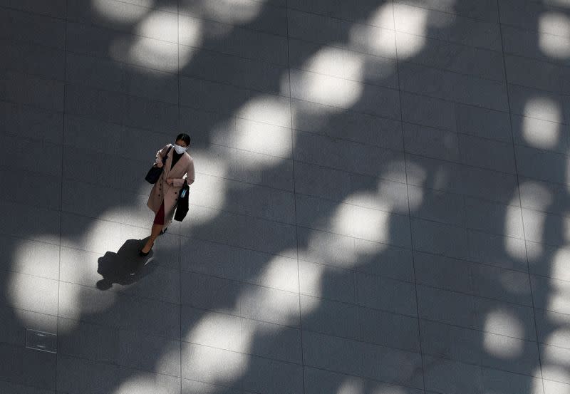 A woman wearing a protective face mask, following an outbreak of the coronavirus disease, walks past inside an almost empty convention complex in Tokyo, Japan